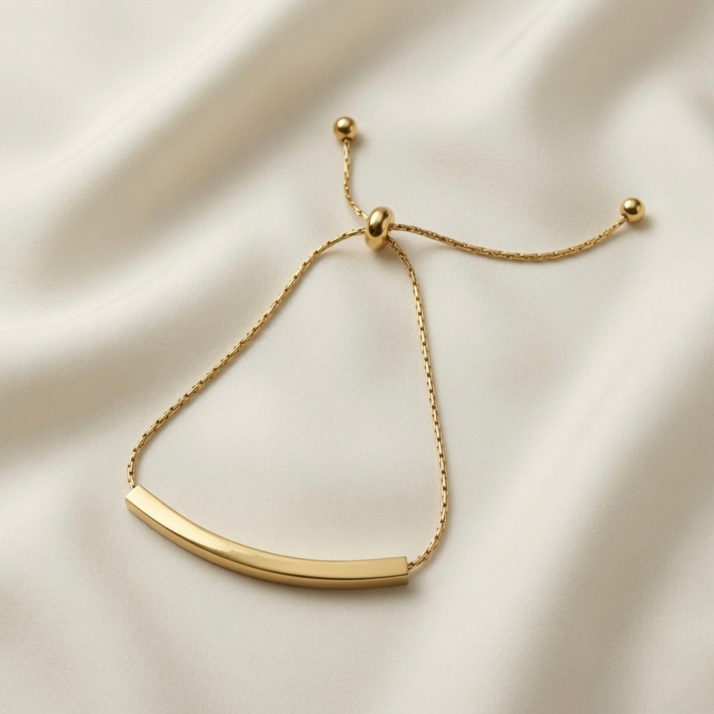 Lover Dream Curved Bar Bolo Bracelet - full flat lay on ivory silk showing complete bracelet open, cable chain, bolo slider and two gold ball tail ends at full length