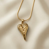 Coeur Or Pendant Necklace - flat lay on ivory silk showing open gold lattice elongated heart with organic filigree web pattern on snake chain