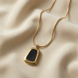 Tableau Noir Pendant Necklace - close-up on ivory silk showing black enamel insert, double-stepped gold inner ridge and pendant proportions