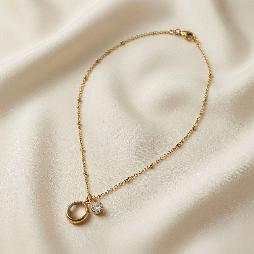 Lune Dorée Crystal Duo Pendant Necklace - full flat lay on ivory silk showing complete satellite ball chain with lobster clasp extender and dual pendant centrepiece of moonstone cabochon and crystal zirconia