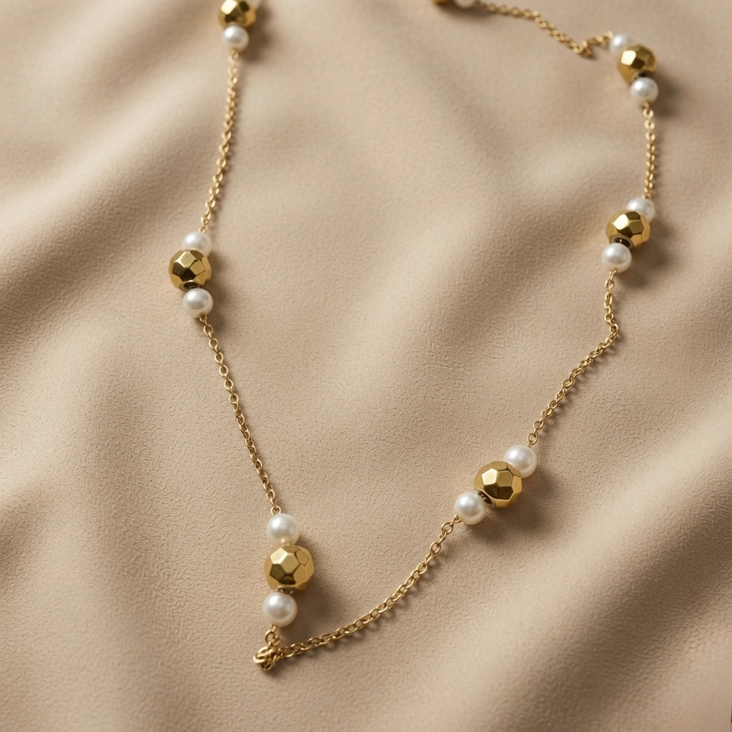 Perle Dorée Station Necklace - macro close-up on taupe silk showing faceted gold bead multifaceted surface and pearl lustre detail