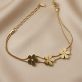 Trois Fleurs Double Snake Chain Bracelet in All Gold - flat lay on taupe silk showing three gold daisies from alternate angle, double snake chain construction and lobster clasp extender detail