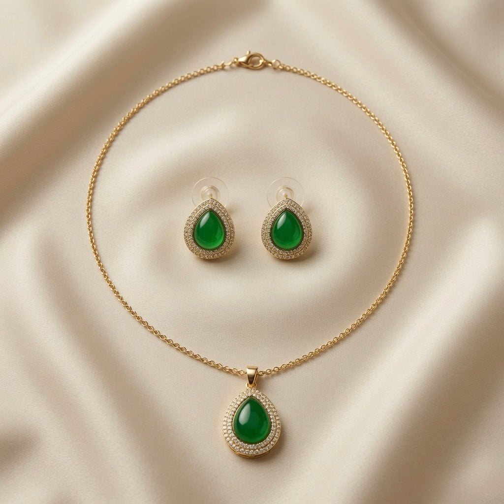 Impériale Jade Pavé Jewellery Set - flat lay on ivory silk showing matching pendant necklace and stud earrings with emerald green cabochon and pavé double halo