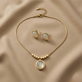 Lune Blanche Cabochon Jewellery Set - full flat lay on taupe silk showing complete snake chain with lobster clasp extender, gold cube bead row, oval pendant and round stud earrings with butterfly push-backs