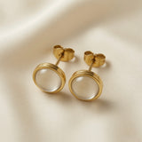 Lune Blanche Cabochon Earrings - macro close-up on ivory silk showing pair of round white moonstone-effect cabochon studs in double-ridged gold bezel with butterfly push-back fastenings