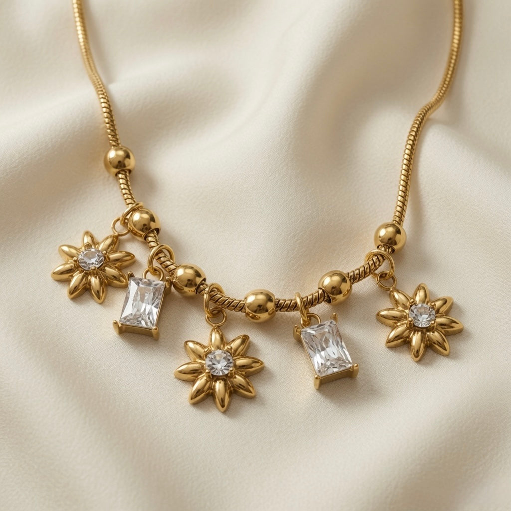 Soleil Baguette Fringe Charm Set necklace - macro close-up on ivory silk showing three ridged gold sunflower charms with round crystal centres and two emerald-cut baguette crystal drops in four-prong settings on alternating ball and barrel station snake chain