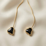 Coeur Noir Bolo Lariat Necklace - macro close-up on ivory silk showing two faceted black crystal hearts in smooth gold bezels side by side, rose-cut dark fire faceting detail