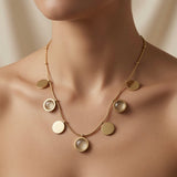 Sept Lunes Disc Station Necklace - worn on mannequin collarbone showing seven alternating gold disc and moonstone circle pendants fanning across chest in celestial arc composition