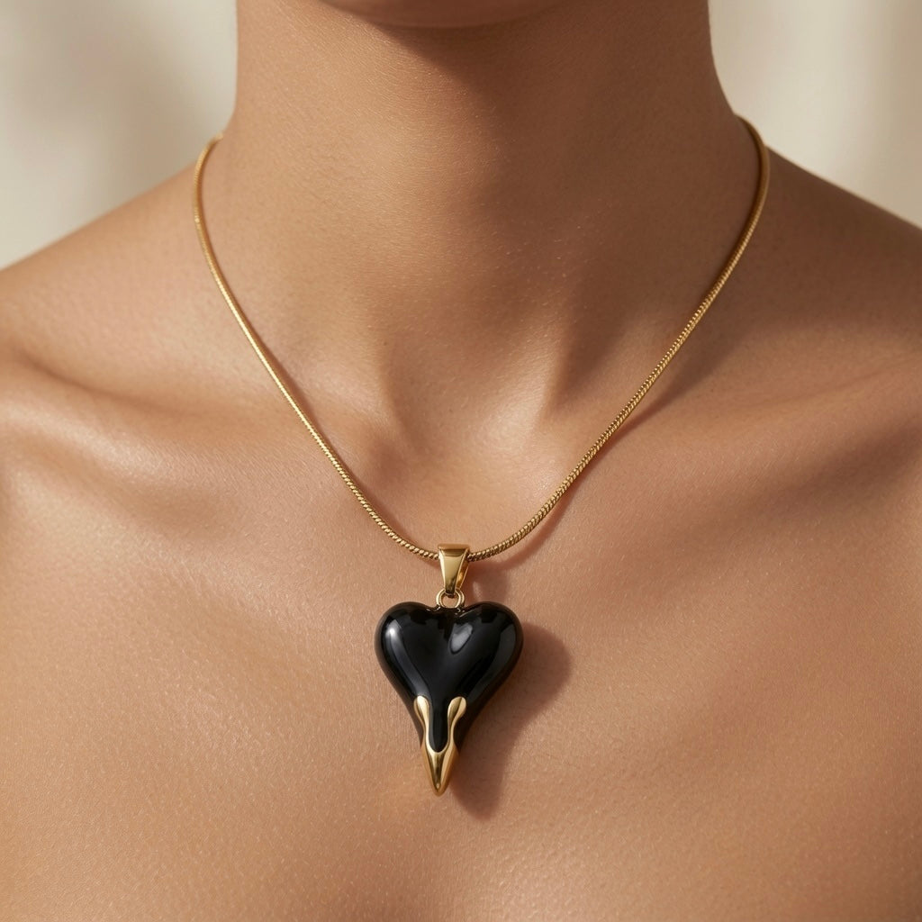 Coeur Noir Pendant Necklace - worn on model sternum showing black enamel heart at chest centre, gold drip tips and flat snake chain against skin