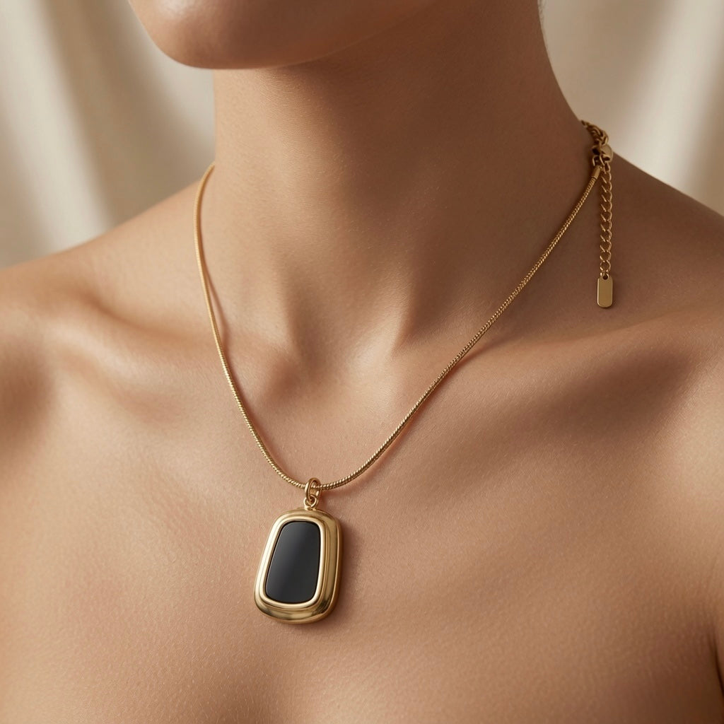 Tableau Noir Pendant Necklace - worn on model collarbone showing black enamel pendant at chest centre, gold frame and flat snake chain against skin
