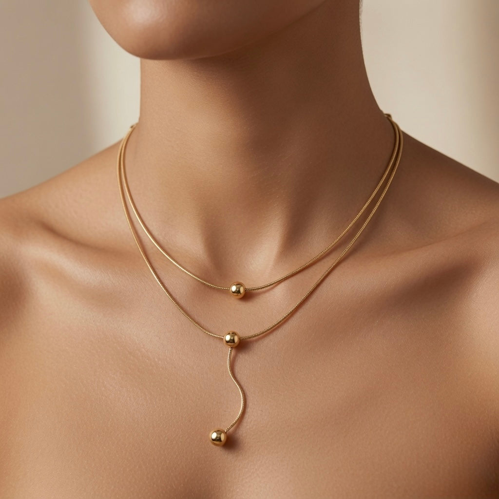 Sphère Lariat Double Layer Snake Chain Necklace - worn on mannequin showing upper choker chain, collarbone station sphere and lariat drop falling in S-curve to sternum with terminating gold ball