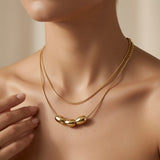 Trio Ovale Double Layer Snake Chain Necklace - worn on model collarbone and sternum showing upper choker chain, lower collarbone chain and three gold oval barrels at chest centre