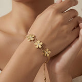 Trois Fleurs Double Snake Chain Bracelet in All Gold - worn on model wrist showing three matte-satin gold daisy flowers with crystal centres fanning across wrist on double snake chain, curb extender visible