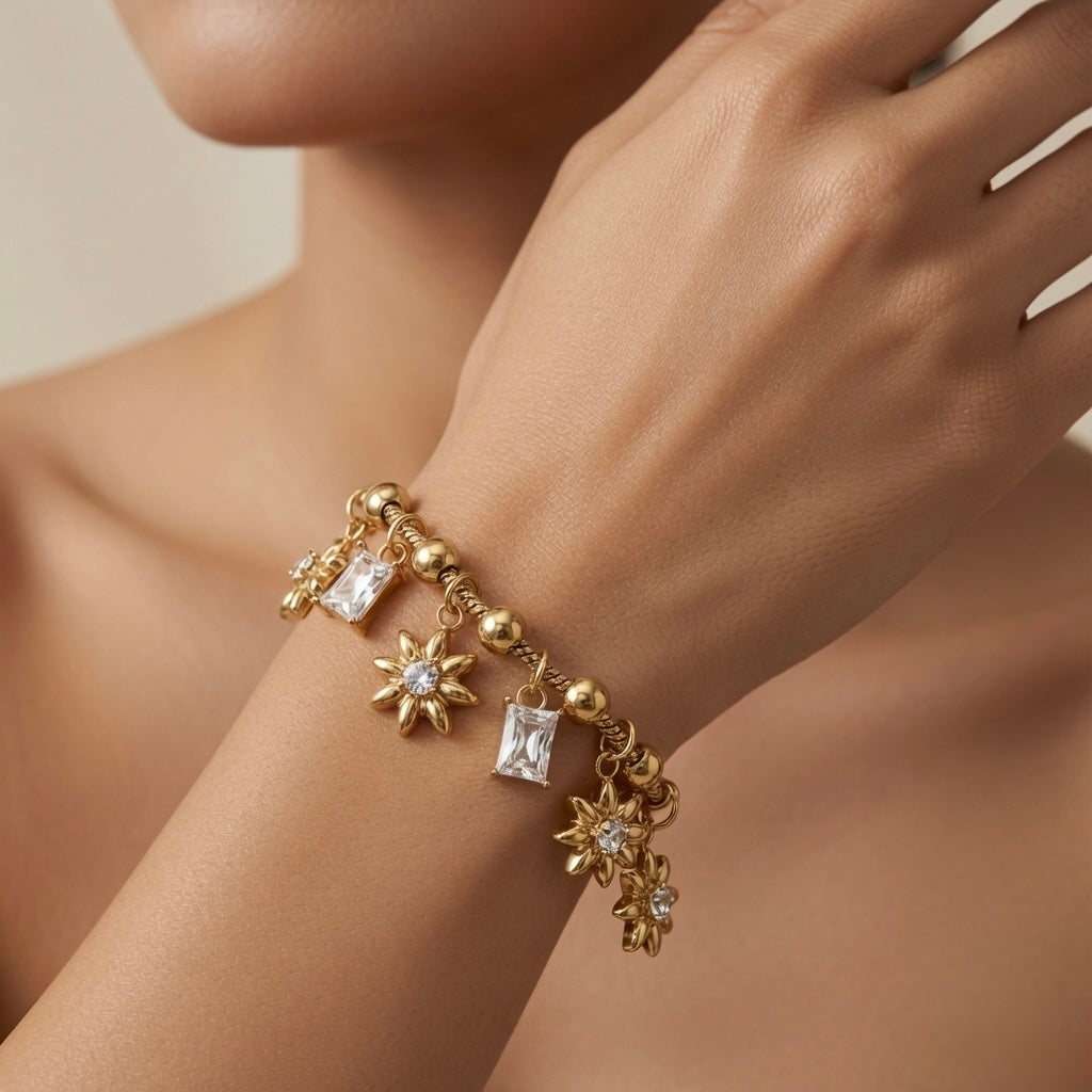 Soleil Baguette Fringe Charm Set bracelet - worn on model wrist and collarbone showing five-charm alternating fringe of three gold sunflowers and two baguette crystal drops swinging freely on ball and barrel station snake chain against warm skin