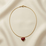 Grand Coeur Rouge Enamel Heart Pendant Necklace - full flat lay on ivory silk showing complete gold box chain with lobster clasp and large three-dimensional puffy heart pendant in deep burgundy-red high-gloss lacquer enamel with continuous warm gold bezel frame