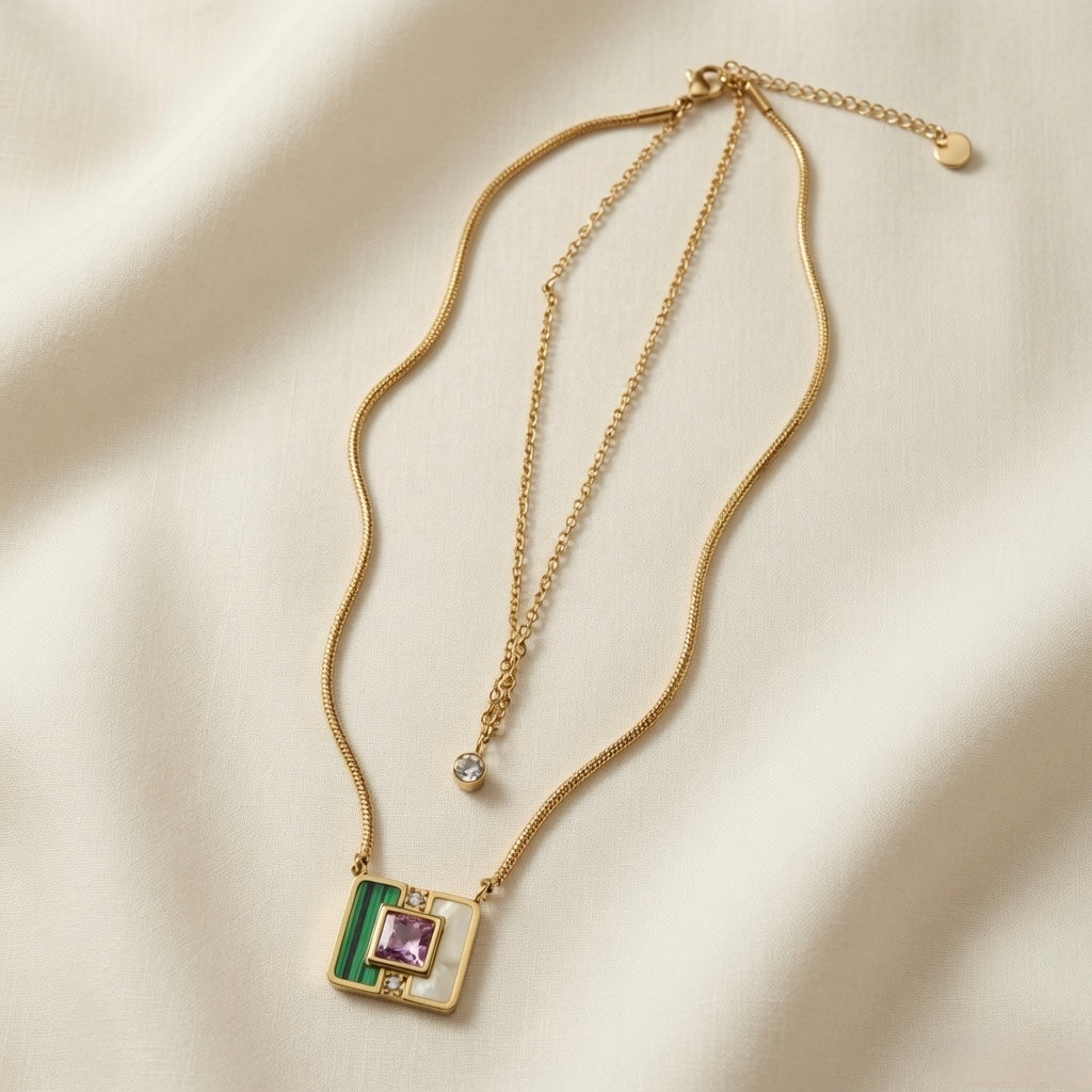 Malachite Amethyst Square Layer Necklace Set - full flat lay on ivory silk showing two necklaces: fine cable chain with single round crystal zirconia solitaire drop above and flat herringbone snake chain with large square malachite mother-of-pearl amethyst inlay pendant below, both with lobster clasps and extenders, small round disc tag on cable chain extender