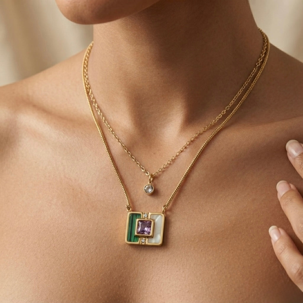 Malachite Amethyst Square Layer Necklace Set - worn on model collarbone and sternum showing two-layer composition: fine cable chain with round crystal solitaire drop at collarbone and flat herringbone chain with malachite amethyst square inlay pendant at sternum against warm skin, model hand at collarbone