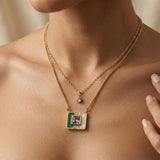 Malachite Amethyst Square Layer Necklace Set - worn on model collarbone and sternum showing two-layer composition: fine cable chain with round crystal solitaire drop at collarbone and flat herringbone chain with malachite amethyst square inlay pendant at sternum against warm skin, model hand at collarbone