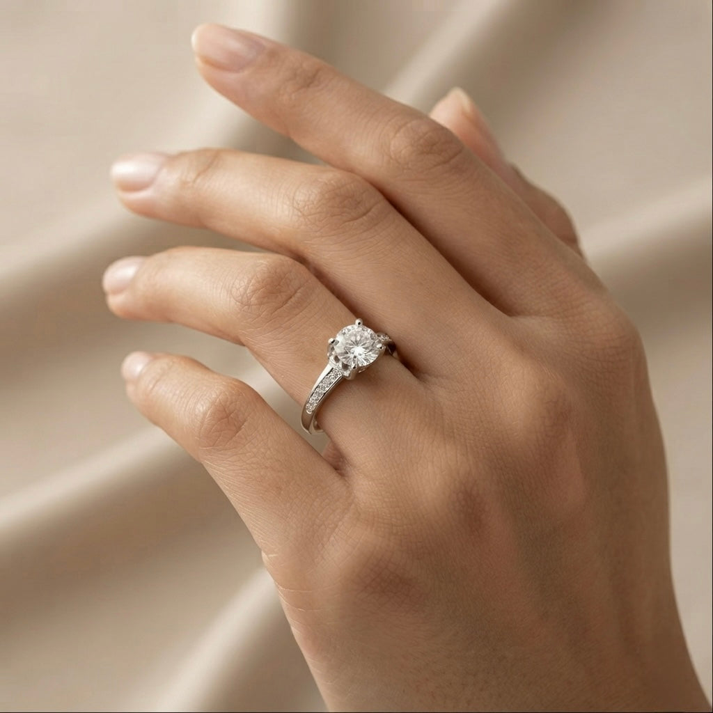 Lumière Solitaire Pavé Adjustable Ring - worn on model ring finger against ivory silk showing round brilliant crystal zirconia solitaire in four-prong cathedral setting with pavé crystal zirconia shoulder accents on rhodium-plated silver-tone adjustable band