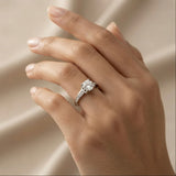 Lumière Solitaire Pavé Adjustable Ring - worn on model ring finger against ivory silk showing round brilliant crystal zirconia solitaire in four-prong cathedral setting with pavé crystal zirconia shoulder accents on rhodium-plated silver-tone adjustable band