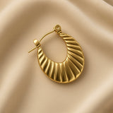 Soleil Fluted Oval Hoop Earrings - single earring macro on champagne silk showing complete oval hoop with deep diagonal fluted ribbing across full face, hinged latch-back clasp with smooth gold pin extended, warm 18K gold surface with alternating highlight ridges and shadow grooves