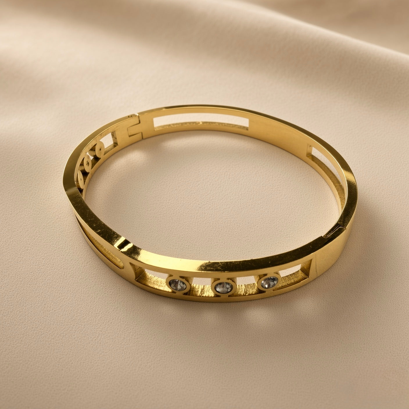 Arcade Crystal Lattice Hinged Bangle Set - crystal bangle overhead view on champagne silk showing complete bangle from above: wide flat-band mirror-polished gold top surface, open-work geometric lattice with five bezel-set crystal zirconia stones on front arc, hinged clasp mechanism at back, clean rectangular cross-section profile