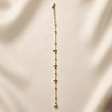 Rosette Bud Station Chain Bracelet - full length flat lay on champagne silk with natural light shadow showing complete bracelet: fine gold cable chain with gold ball stations and three rose bud charm stations with round rose-pink crystals and dark green enamel marquise sepals, lobster clasp and curb-link extender chain at top