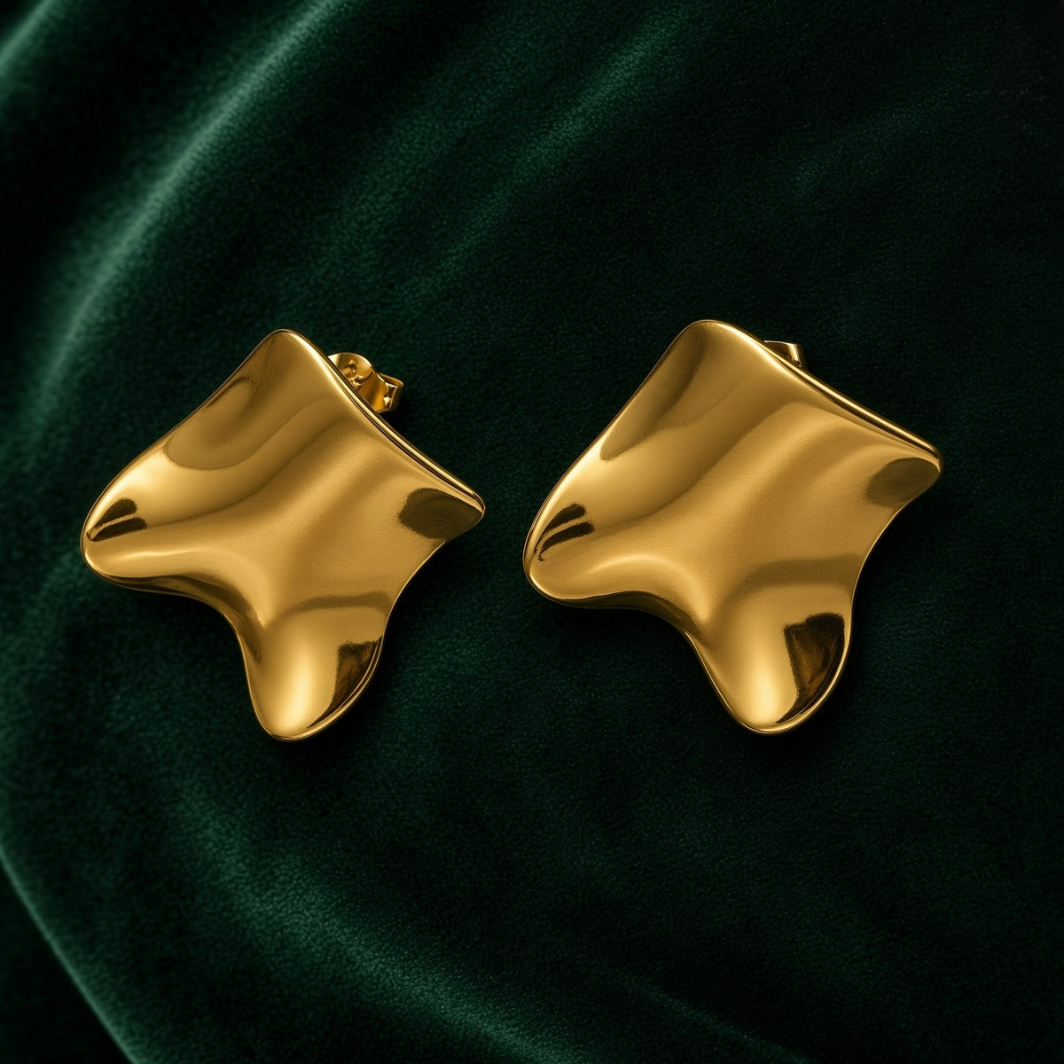 Gold Sculptural Wave Square Stud Earrings - pair face-on on deep forest green velvet showing both earrings side by side: generously proportioned wave-distorted square studs in high mirror-polish 18K gold, deeply warped three-dimensional form with concave hollows and convex peaks, warm gold mirror-polish surface catching light from multiple angles simultaneously