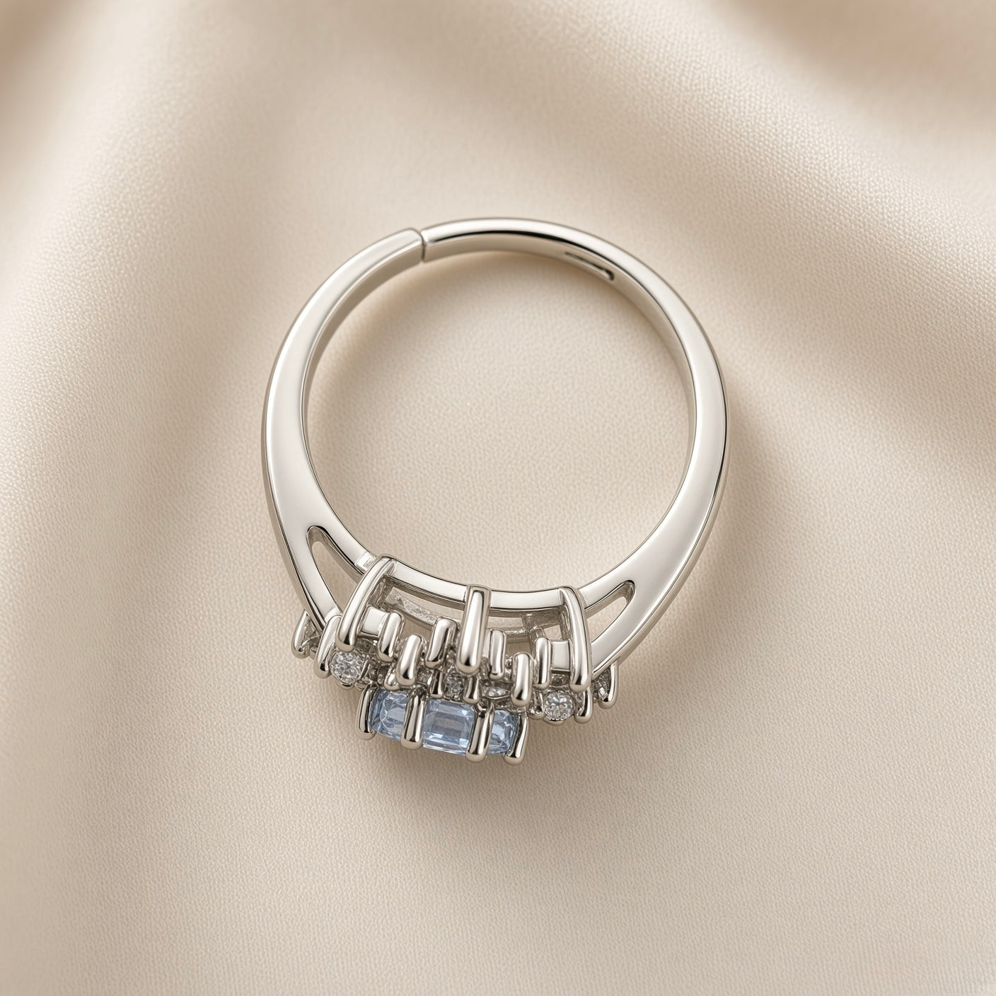 Sky Blue Crystal Snowflake Halo Ring - side profile on ivory satin showing ring band construction and second ring: split shank silver ring with three princess-cut pale blue crystal zirconia in bar claw settings flanked by small round white crystals, two parallel rails splitting at front and rejoining at back