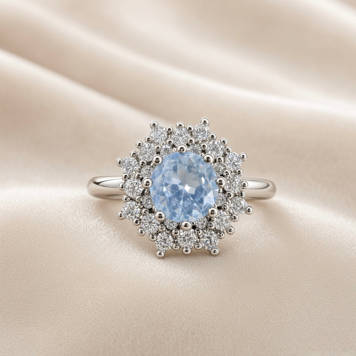 Sky Blue Crystal Snowflake Halo Ring - face-on on ivory satin showing complete ring: round pale sky blue crystal zirconia centre stone in multi-prong setting surrounded by dramatic double starburst halo of round brilliant white crystal zirconia stones and polished silver ball details radiating in snowflake pattern, plain polished round-wire silver band