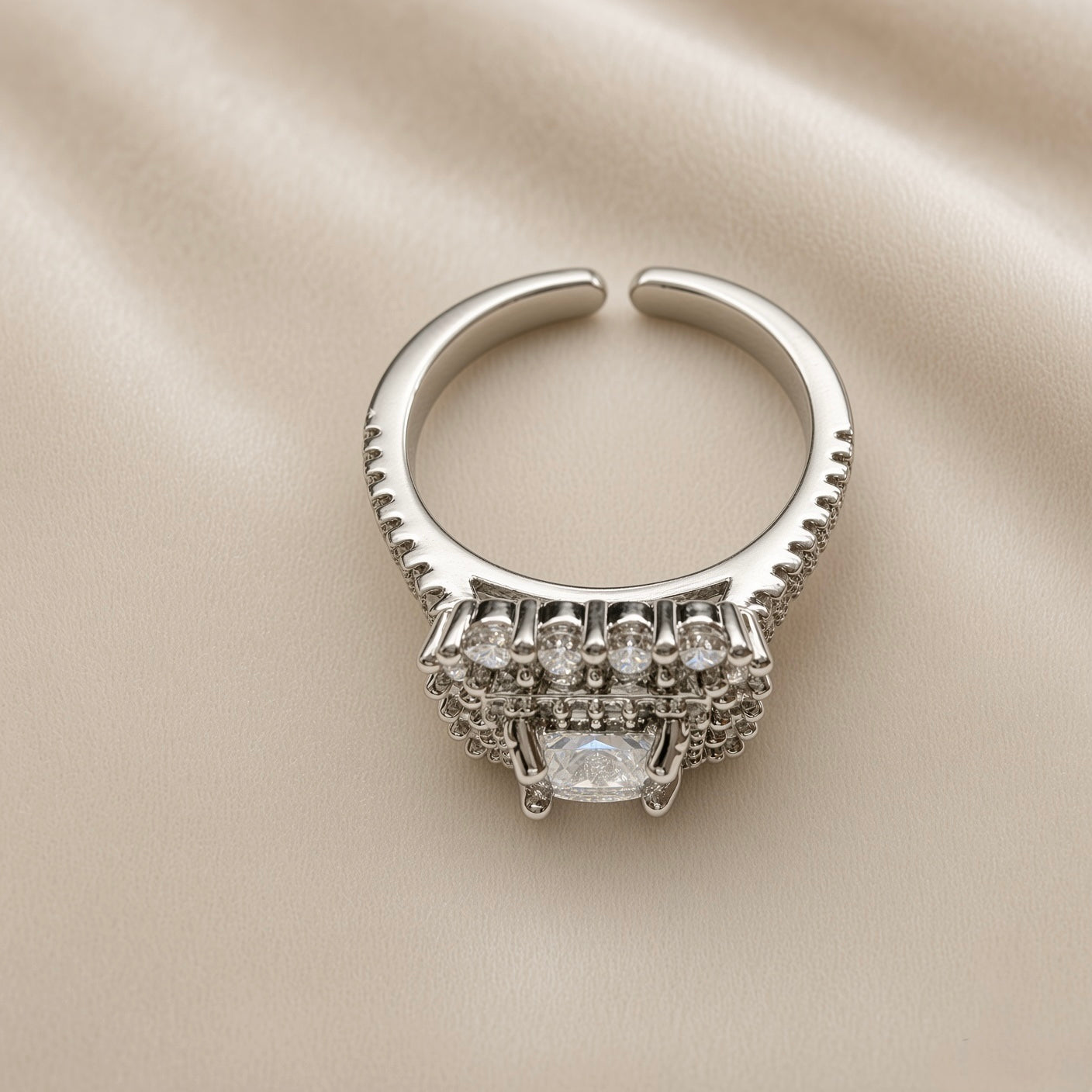 Princess Cut Double Halo Split Shank Adjustable Ring - back/underside view on ivory satin showing open adjustable band and gallery underside: open-C adjustable band back construction with pavé rails visible on both sides, layered gallery underside construction showing full ring head depth, five round brilliant white crystals visible in top row of gallery, diamond-clear marquise crystal visible at base of gallery
