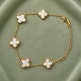 White Clover Station Bracelet Gold Milgrain - circular flat lay on sage green satin showing complete bracelet in loop: five white mother-of-pearl clover motifs with milgrain gold bead borders on fine gold cable link chain, lobster clasp visible at right, white mother-of-pearl fill and milgrain bead border detail clearly visible on all five clover motifs