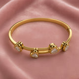 Gold-tone bracelet with four heart-shaped clear stone accents on pink fabric
