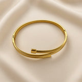 Gold-tone double band open cuff bracelet with polished bar detail on beige fabric