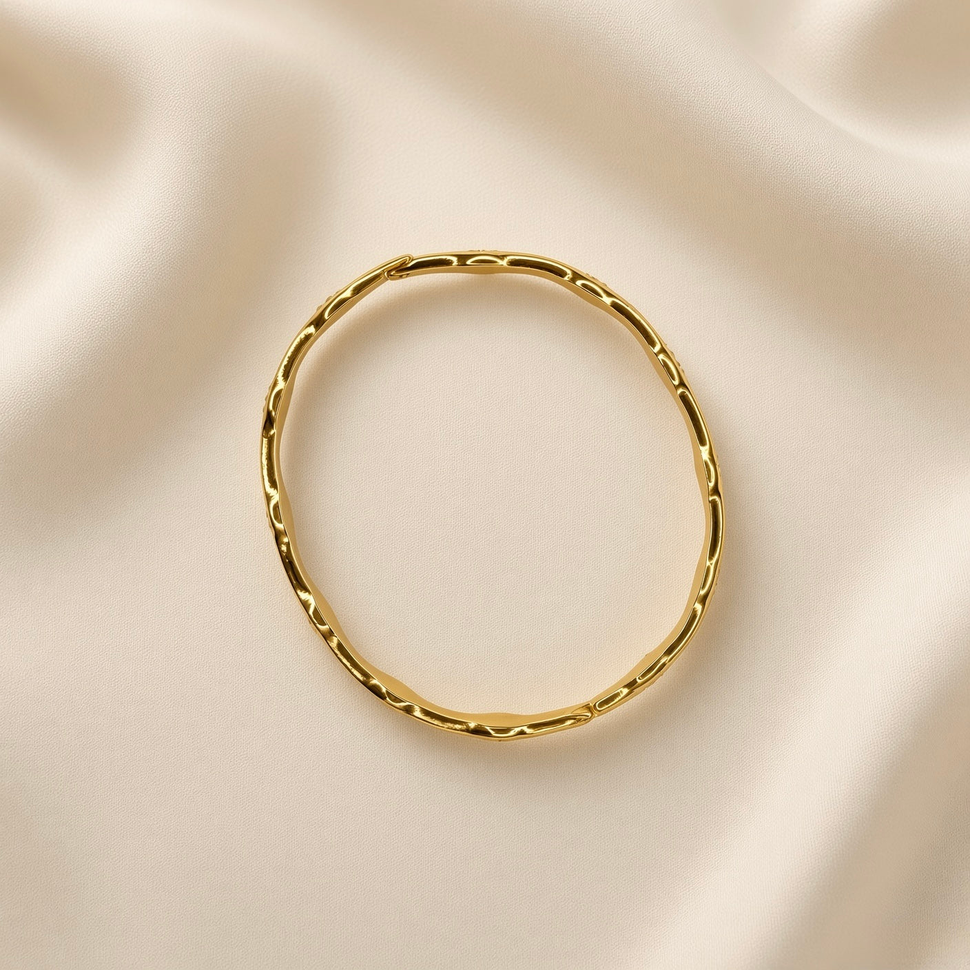 Close-up of a gold-tone scalloped bangle bracelet with clear crystal-style details
