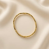 Close-up of a gold-tone scalloped bangle bracelet with clear crystal-style details