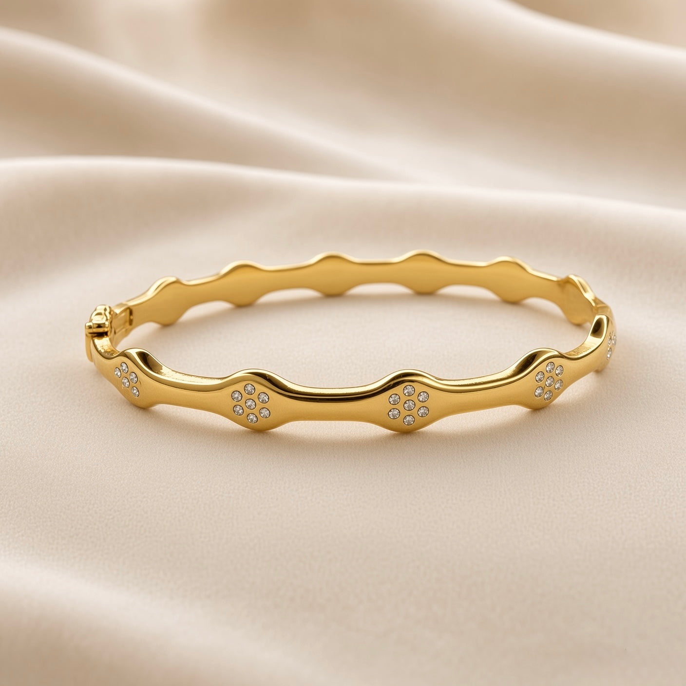 Gold-tone bangle bracelet showing its scalloped wave design and clear accent stones