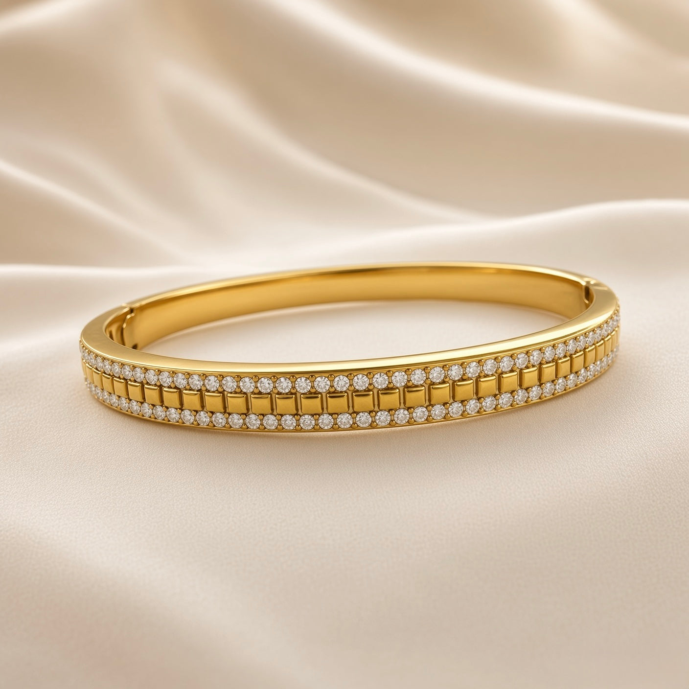Angled view of gold-plated stainless steel clear-stone bangle bracelet on cream fabric
