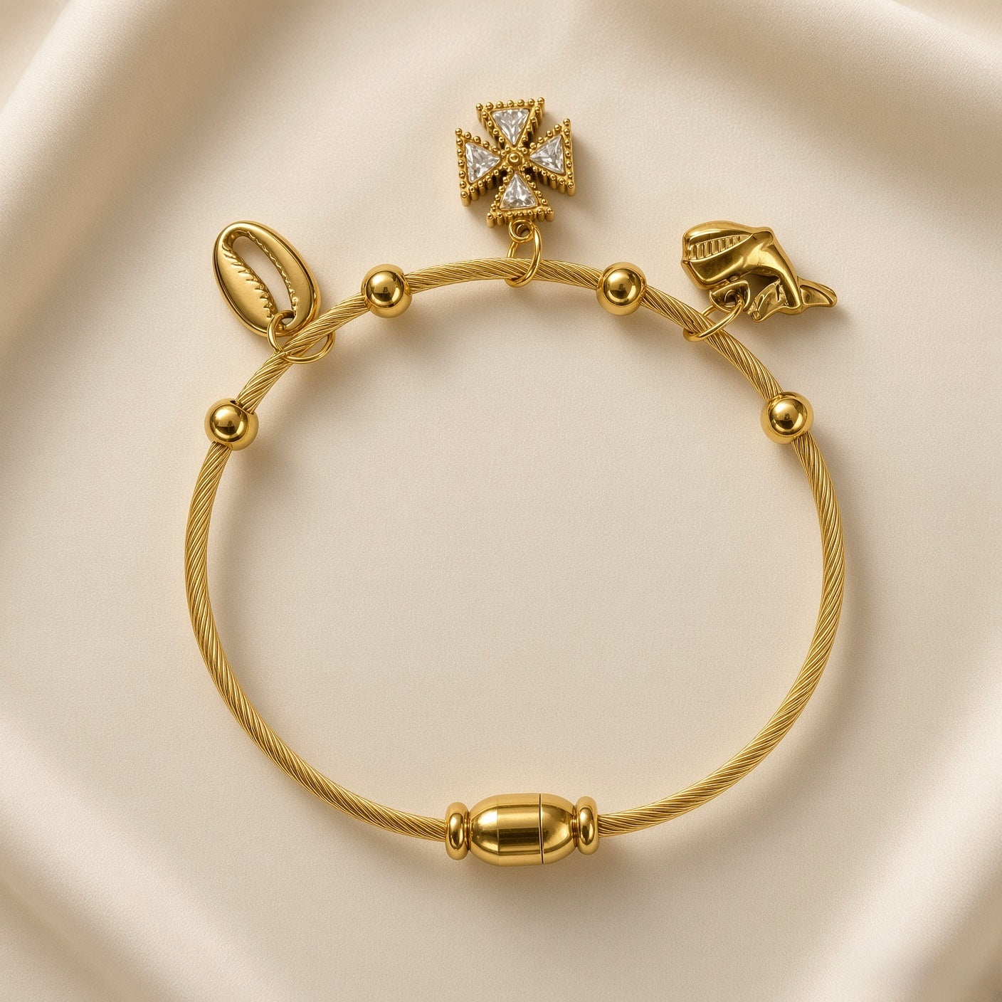 Close-up of gold-plated stainless steel charm bracelet with textured wire band and decorative charms