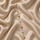 Gold Star and Pearl Station Bracelet Milgrain - circular flat lay on cream satin: fine gold cable chain with six alternating stations, three puffy milgrain-border gold five-pointed star charms and three round white freshwater pearl stations, lobster clasp with engraved gold bar tag at bottom
