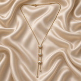 Pearl Heart Lariat Necklace Triple Station Crystal Drop Gold - full flat lay on cream satin: complete lariat Y-necklace showing fine box chain meeting at V-point, three white-cream pearl heart bezel stations descending on double-strand tassel drop, two round crystal bezel terminators at base, lobster clasp with curb extender chain at top