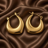 Chunky Crescent Moon Hoop Earrings Gold Mirror Polish - on model lifestyle: single hoop worn on ear of model with low chignon and white blazer, chunky crescent moon gold hoop framing jawline with bold sculptural warm gold presence, click-hoop clasp visible at lower body, high mirror-polish warm gold surface glowing against neutral background