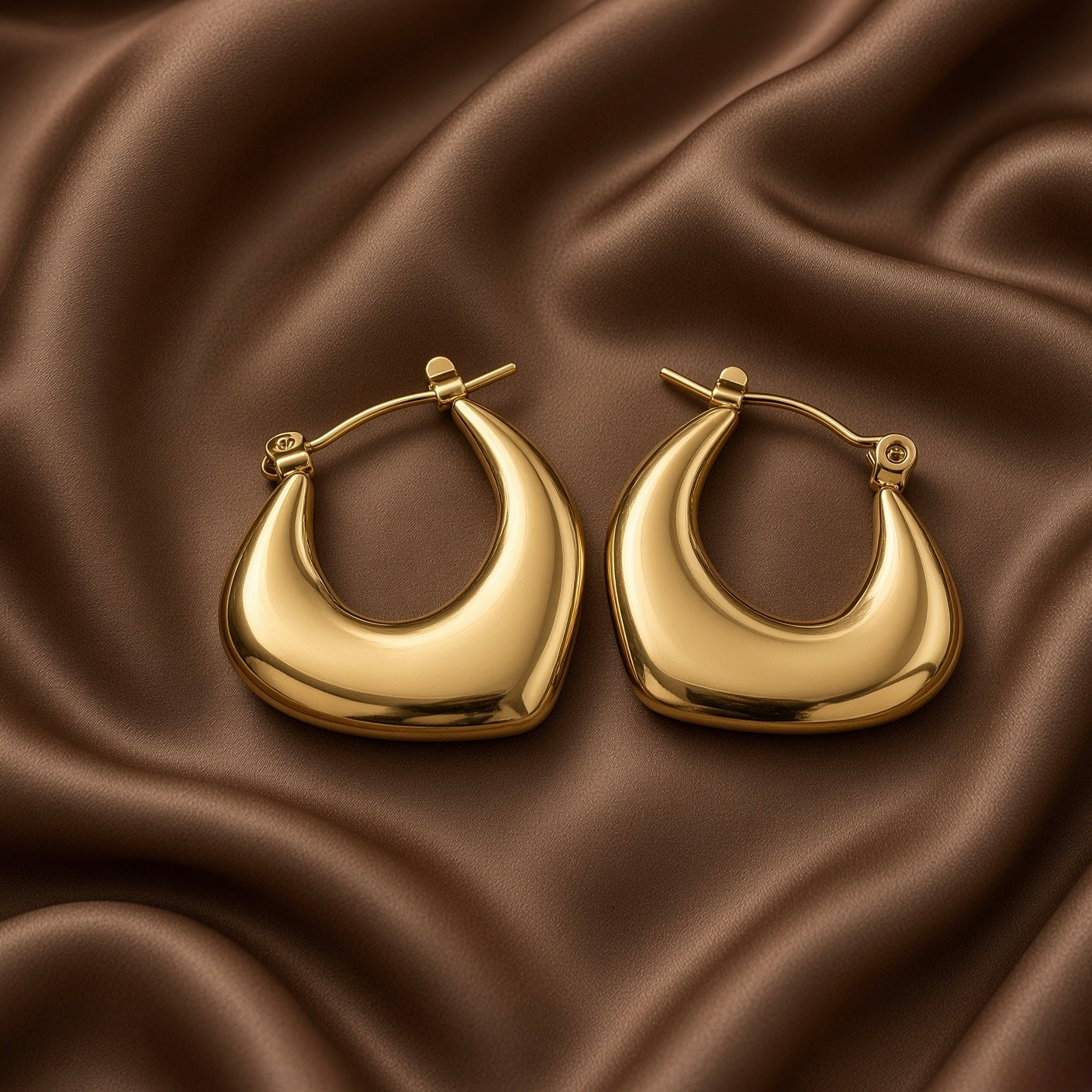 Chunky Crescent Moon Hoop Earrings Gold Mirror Polish - single hoop macro on dark brown satin: close detail of one crescent moon hoop showing full sculptural form, wide domed convex mirror-polish warm gold front surface, deep concave inner crescent negative space, click-hoop lever clasp mechanism at lower right, fine gold wire post at top