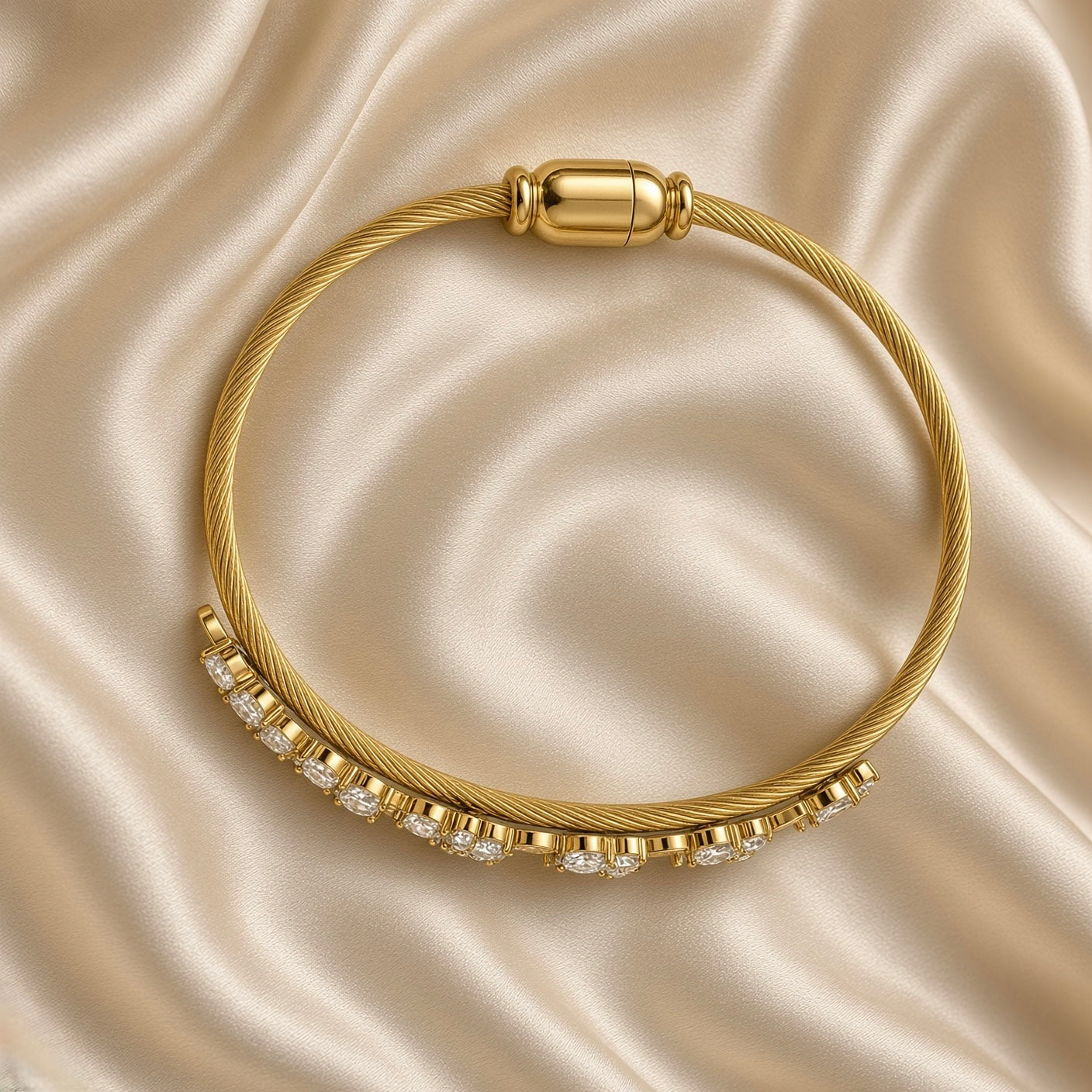 Gold Twisted Wire Bangle Floral Marquise Crystal Garland Magnetic Clasp - angled flat lay on cream satin: three-quarter view of bangle showing twisted rope wire texture detail and full floral crystal garland with marquise navette and round brilliant white crystal stones at varied orientations in warm gold prong settings, capsule magnetic clasp at top, cream satin background