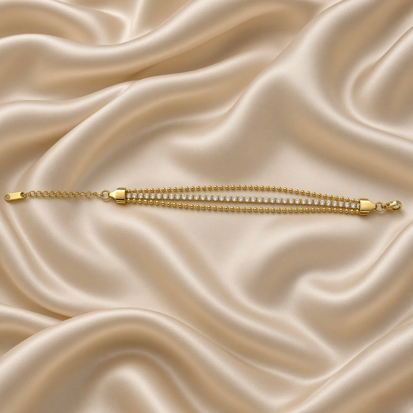 Gold Three Row Bracelet Crystal Tennis Centre Ball Bead Chain Lobster Clasp - extended horizontal flat lay on cream satin: bracelet fully extended in straight lay showing complete three-row construction from tapered shield end cap on left through full bead-crystal-bead parallel row length to lobster clasp and extension chain on right, all three rows visible in parallel at full bracelet length, cream satin background