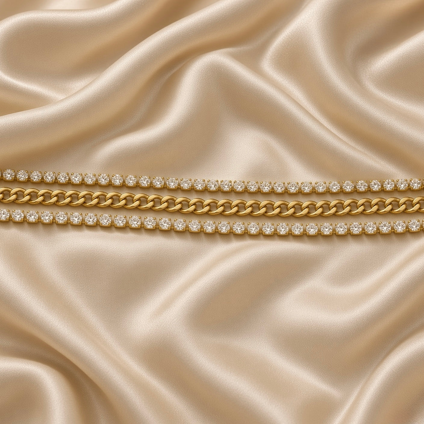 Gold Cuban Link Chain Bracelet Double Crystal Tennis Row Three Row Shield Clasp - overhead straight flat lay on cream satin: full bracelet in straight horizontal lay showing complete parallel three-row architecture from tapered shield end cap on left to lobster clasp and extension chain on right, flat-faced Cuban curb link centre and flanking crystal tennis rows in full-length parallel, cream satin background
