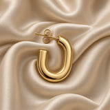 Pair of polished gold-tone U-shaped hoop earrings on champagne satin