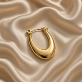 Gold-tone teardrop hoop earring worn on an ear