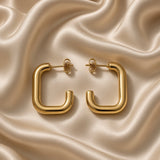Pair of polished gold-tone square U-shaped hoop earrings on champagne satin