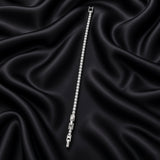 Full-length view of slim silver-tone crystal tennis bracelet on black satin